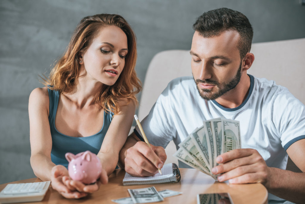 couple planning family budget with piggy bank and dollars in living room