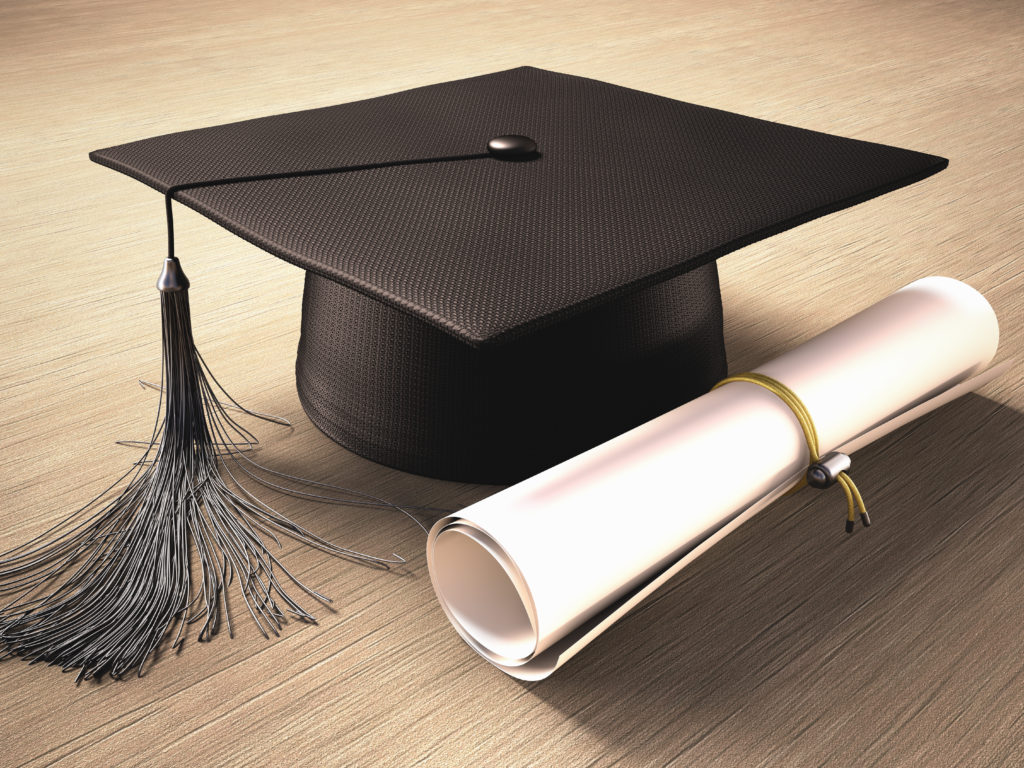 Graduation cap with diploma over the table. Clipping path included.