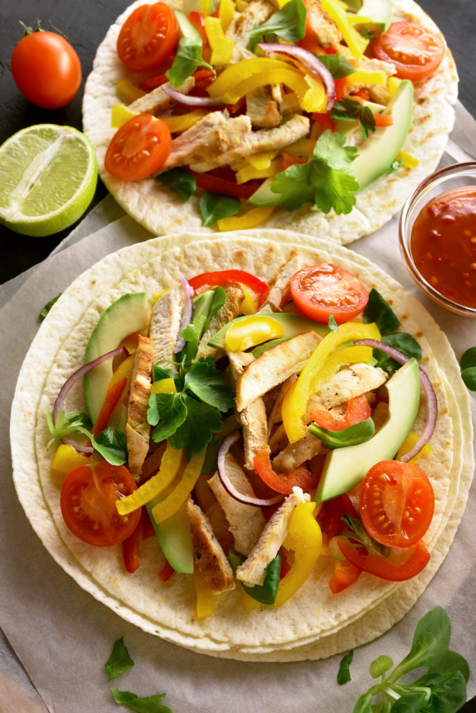 Tasty tacos with chicken meat and avocado, bell pepper, tomatoes. Top view